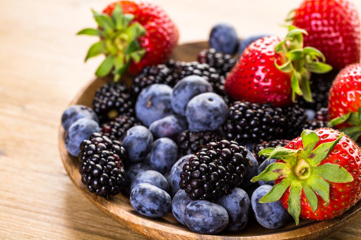 A variety of colorful berries in a wooden dish