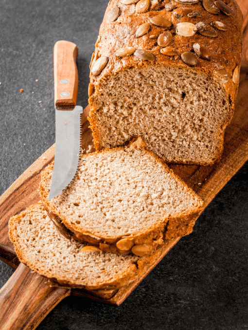 A loaf of whole grain bread with seeds and a few slices cut