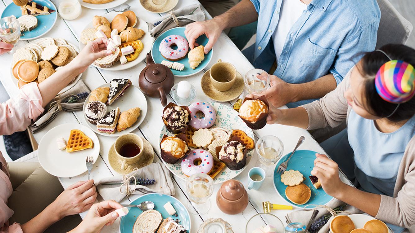 Top-down view of people at a table filled with donuts and other pastries