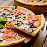 A supreme pizza with a slice being lifted with a serving spatula