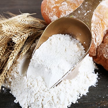 A wooden scoop of whole wheat flour