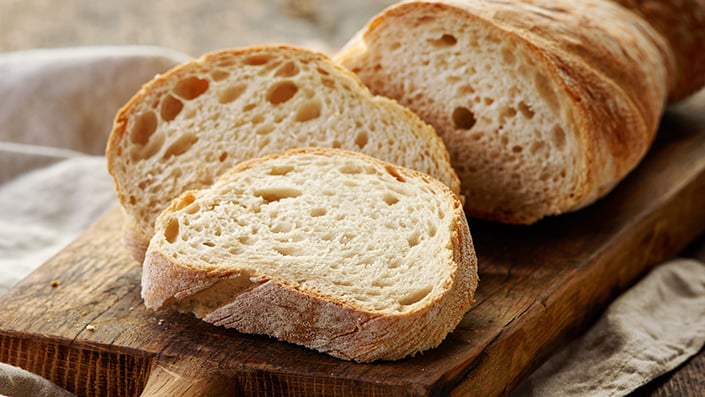 Slices of crusty white bread on a wooden serving board