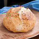 A round loaf of crusty bread on a wooden cutting board