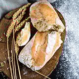 A loaf of sorghum flour bread torn in half on a wooden cutting board