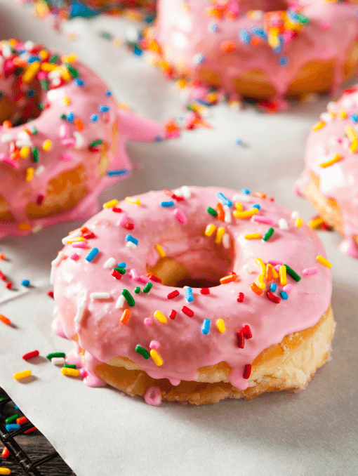 A donut covered in light pink icing and multicolored sprinkles