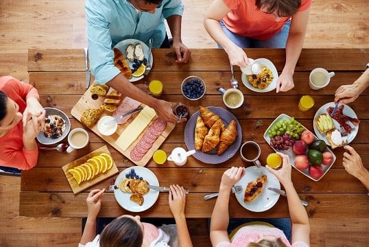 A group of friends seen from above while eating a healthy meal on a wooden table