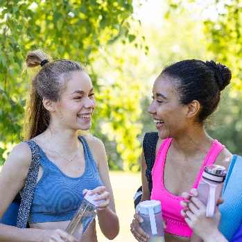 Two women in gym outfits are talking to each other