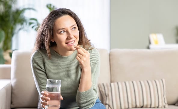 A woman is having a prebiotic snack while sitting on a grey sofa