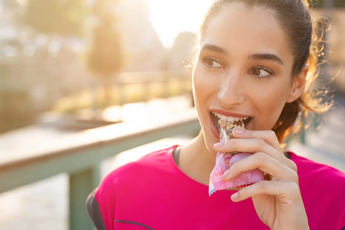 Athletic woman eating a protein bar