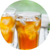 A close-up of glasses of stevia-sweetened iced tea on a picnic bench outside.