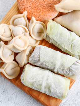 Frozen dumplings and cabbage rolls on a wooden cutting board