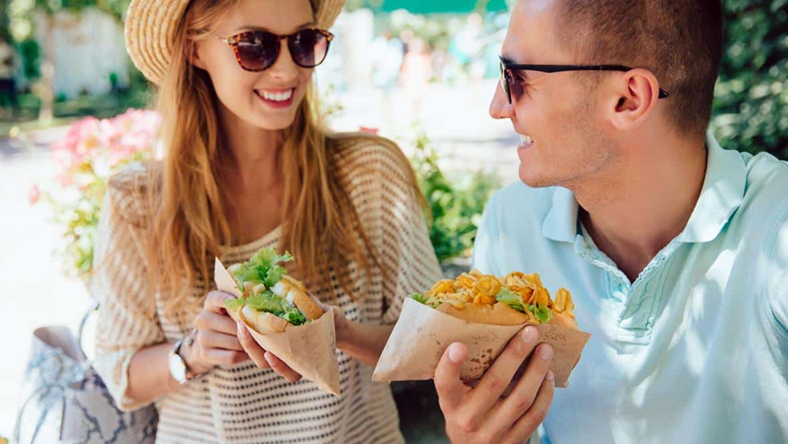 Two people talking and eating food outside