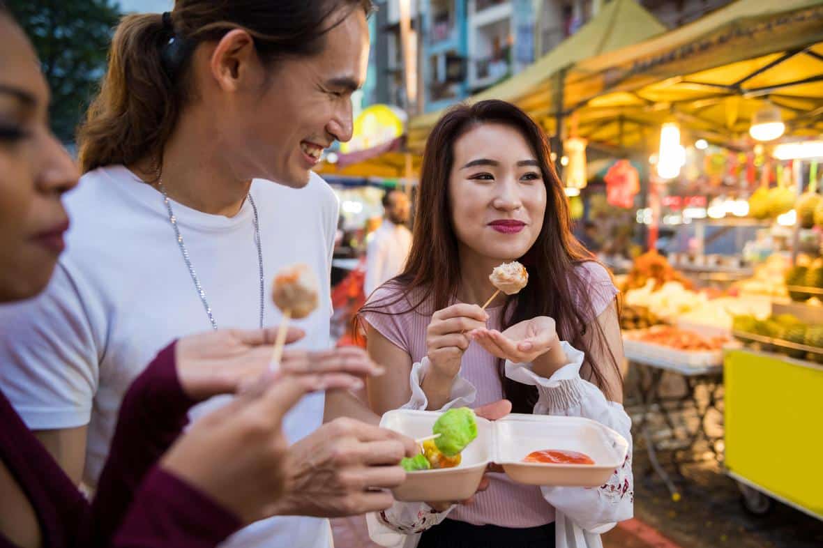 Friends eating local cuisine at a night market GettyImages 959430694 min