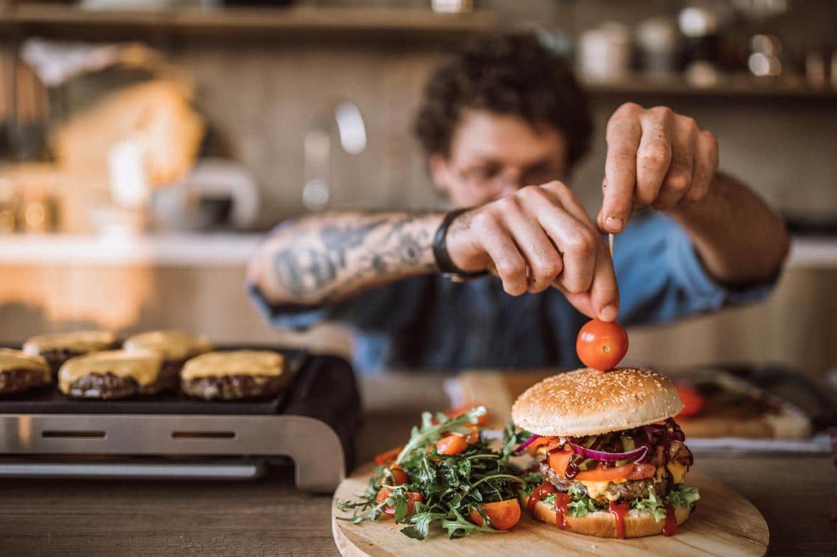 Man preparing a burger with sauce