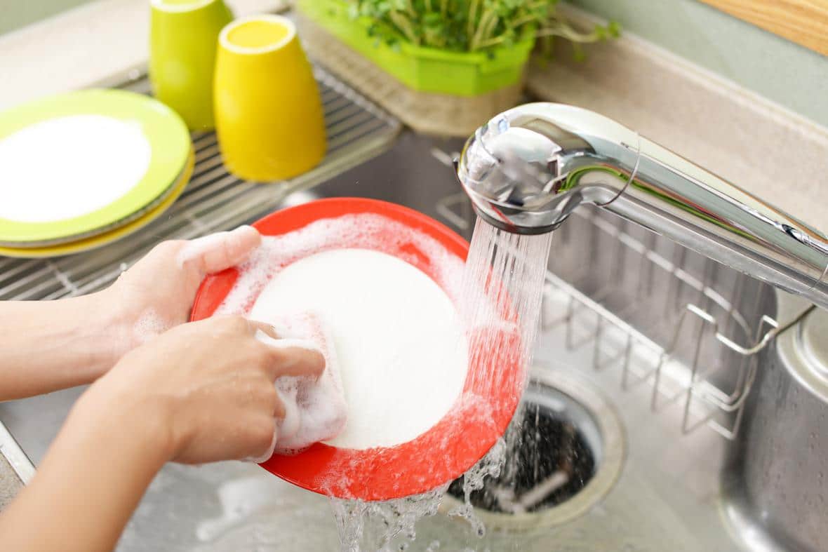 A person washing dishes in a sink