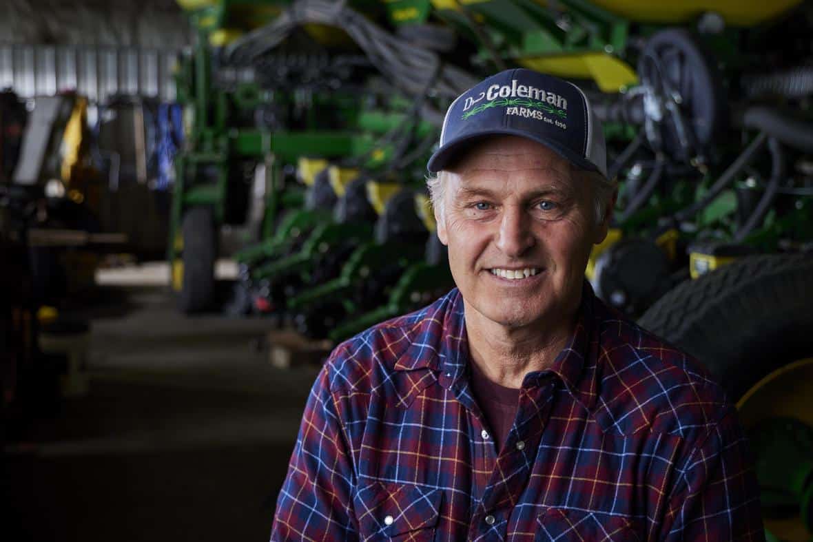 Close up of a farmer looking at the screen and smiling on a green background