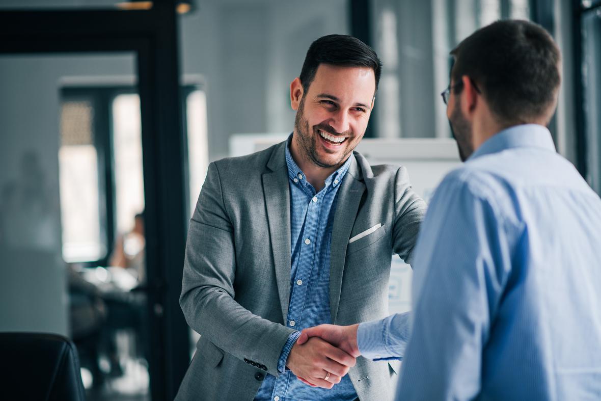 Two happy men shaking hands in an office