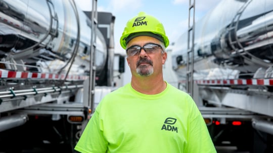 man in green adm shirt in between oil trucks