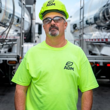 man in green adm shirt in between oil trucks