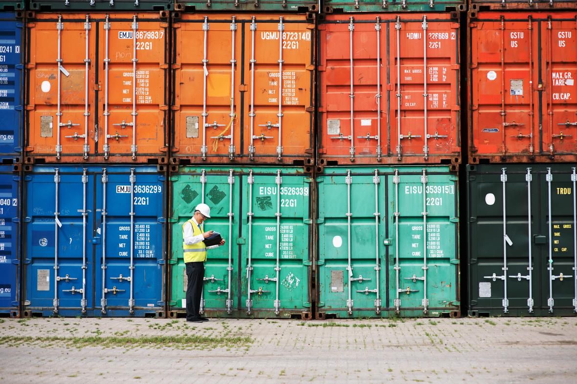 Supervisor tracking orders on a tablet with colorful shipping containers in background