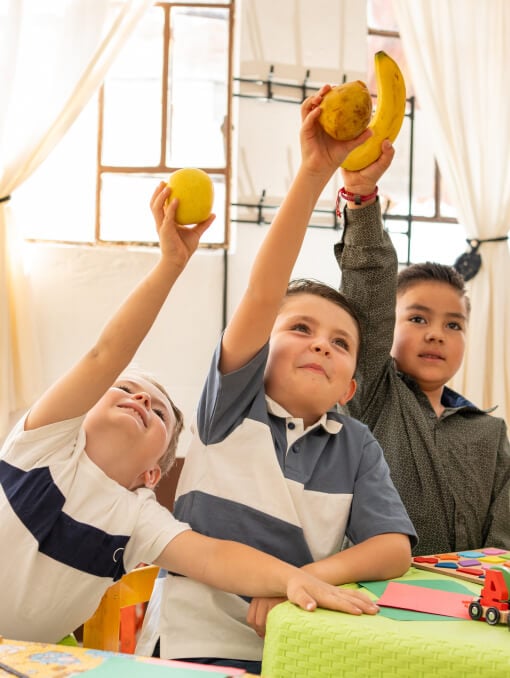 A group of boys holding bananas and fruits
