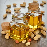 Two glass bottles of oil surrounded by peanuts and peanut shells