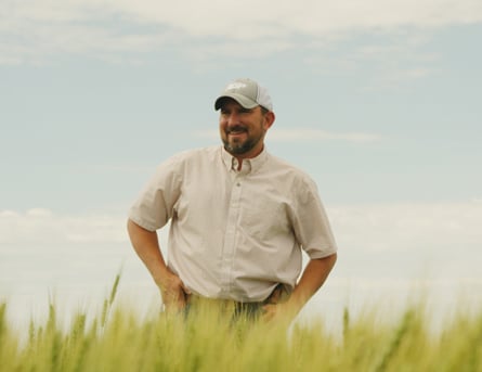 Man standing in a field with hand on hips