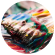 A paintbrush mixing paint on a palette