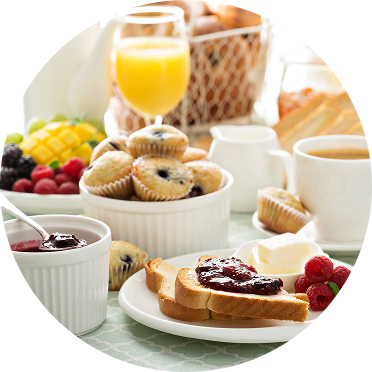 A continental breakfast spread with toast and jam, mini muffins, fruit, tea, and orange juice