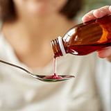 A person pouring liquid into a spoon