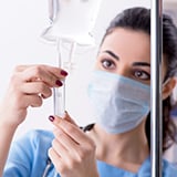 A woman wearing a mask and holding an IV drip