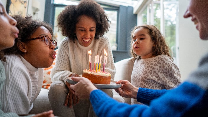 A family blows out the candles on a birthday cake 
