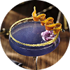 A purple cocktail in a coupe glass with garnishes