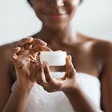 A close-up of a hand holding a jar of cream