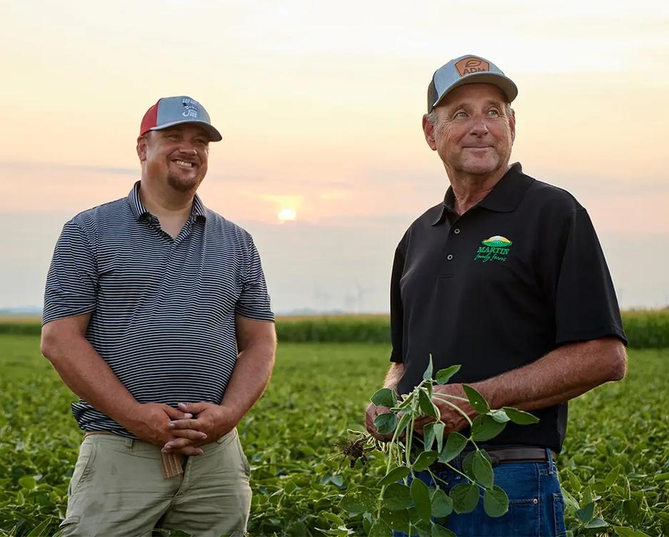 Two farmers standing and talking in field.