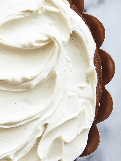 A cake with swirled white vanilla frosting