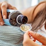 A person pouring medicine into a spoon