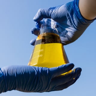 A person’s hands holding a beaker of liquid