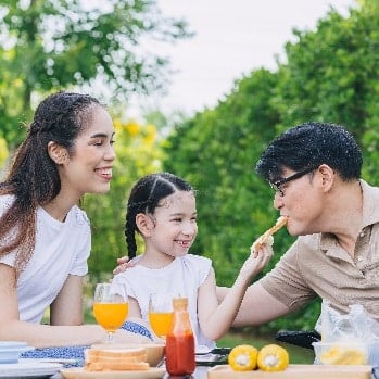 Three people of diverse genders and races are laughing and talking at a table