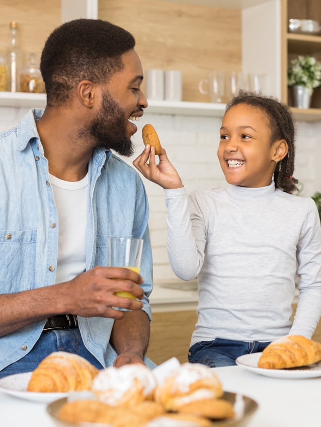 Father and daughter enjoying a sweet cookie together in the kitchen