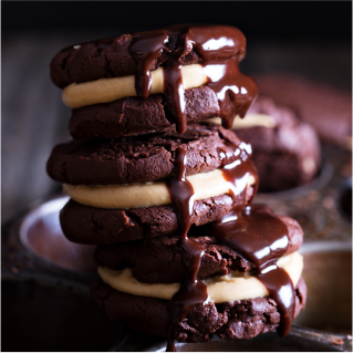 A close up of homemade reduced sugar chocolate cookie sandwiches piled high on a plate.