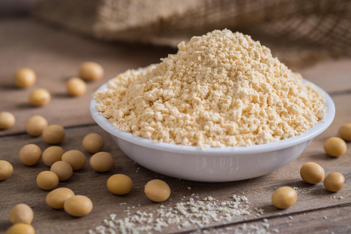 Soybean meal in a bowl with raw soybeans around