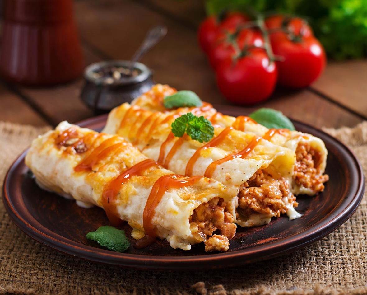 Savory plated enchilada dish with meat, sauce and garnish