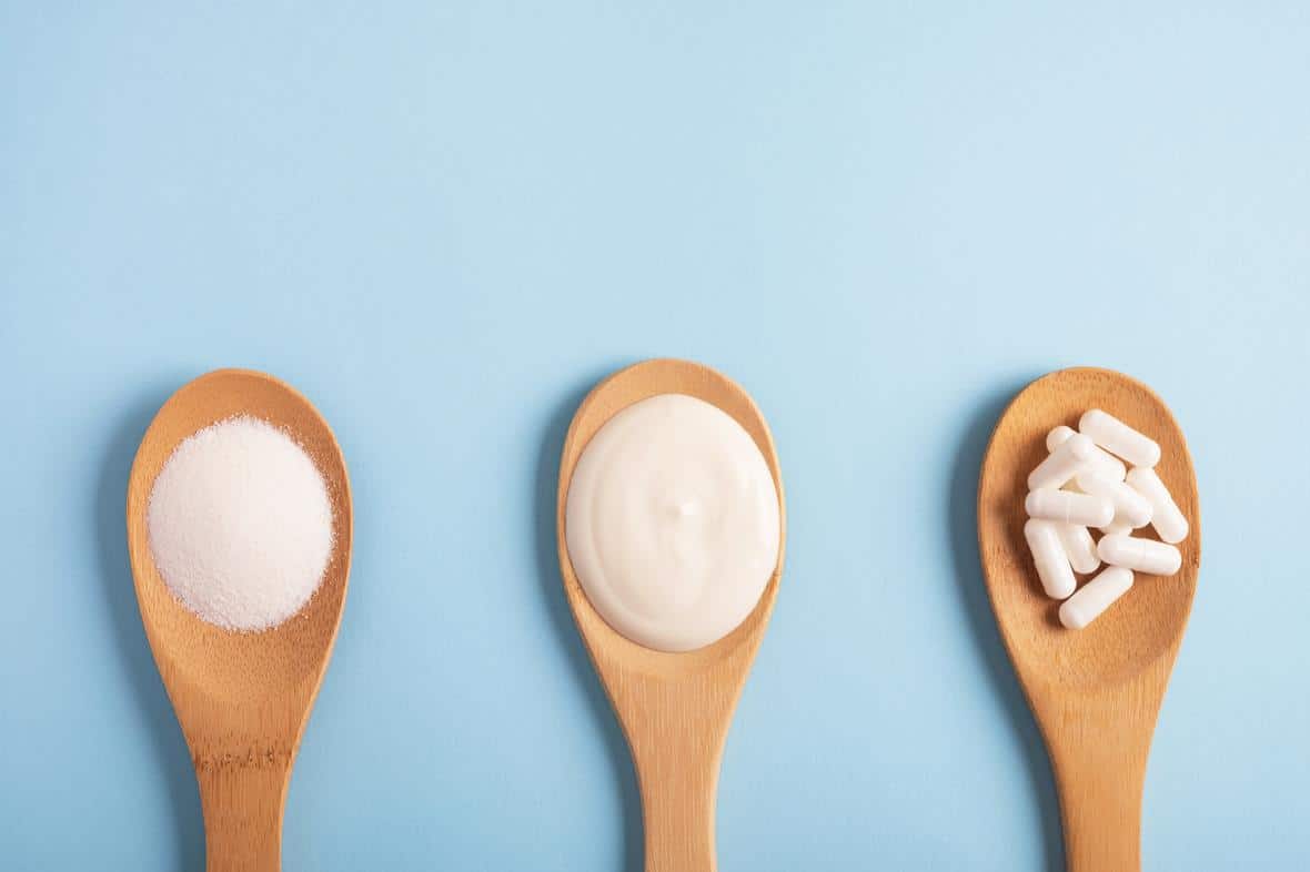 Wooden spoons showing microbiome products (powder, yogurt, capsules)