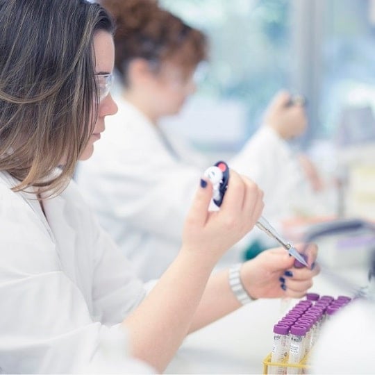 A woman in a white coat is performing an experiment in a lab