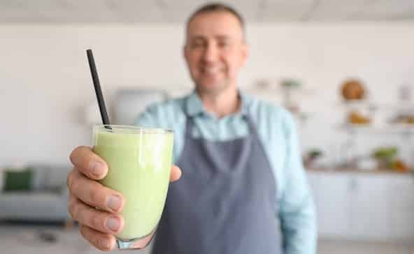 A barman showcases a colorful dairy drink in a bar setting