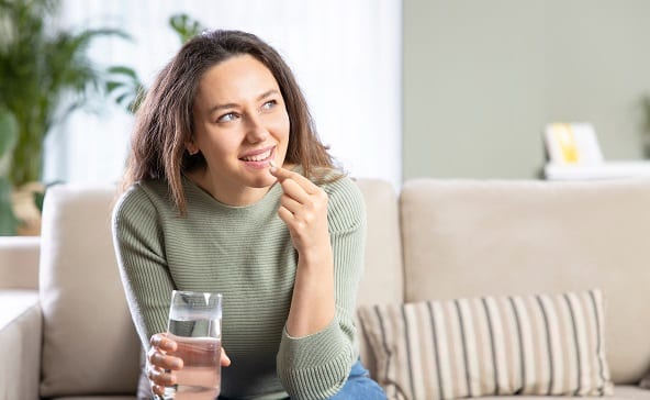 A woman is having a prebiotic snack while sitting on a grey sofa