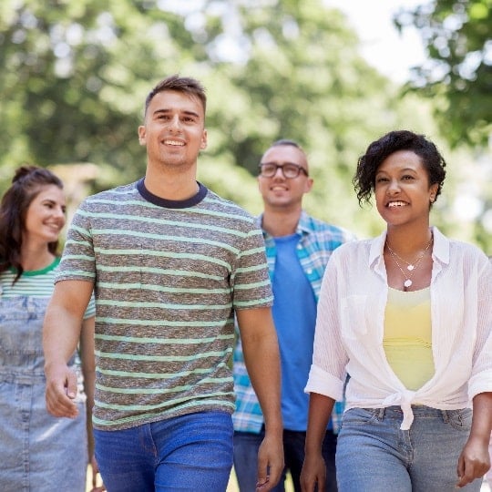 A group of people from diverse races and genders walks towards the camera