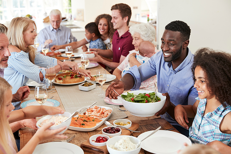 Multi-generation family and friends sitting around table and enjoying meal