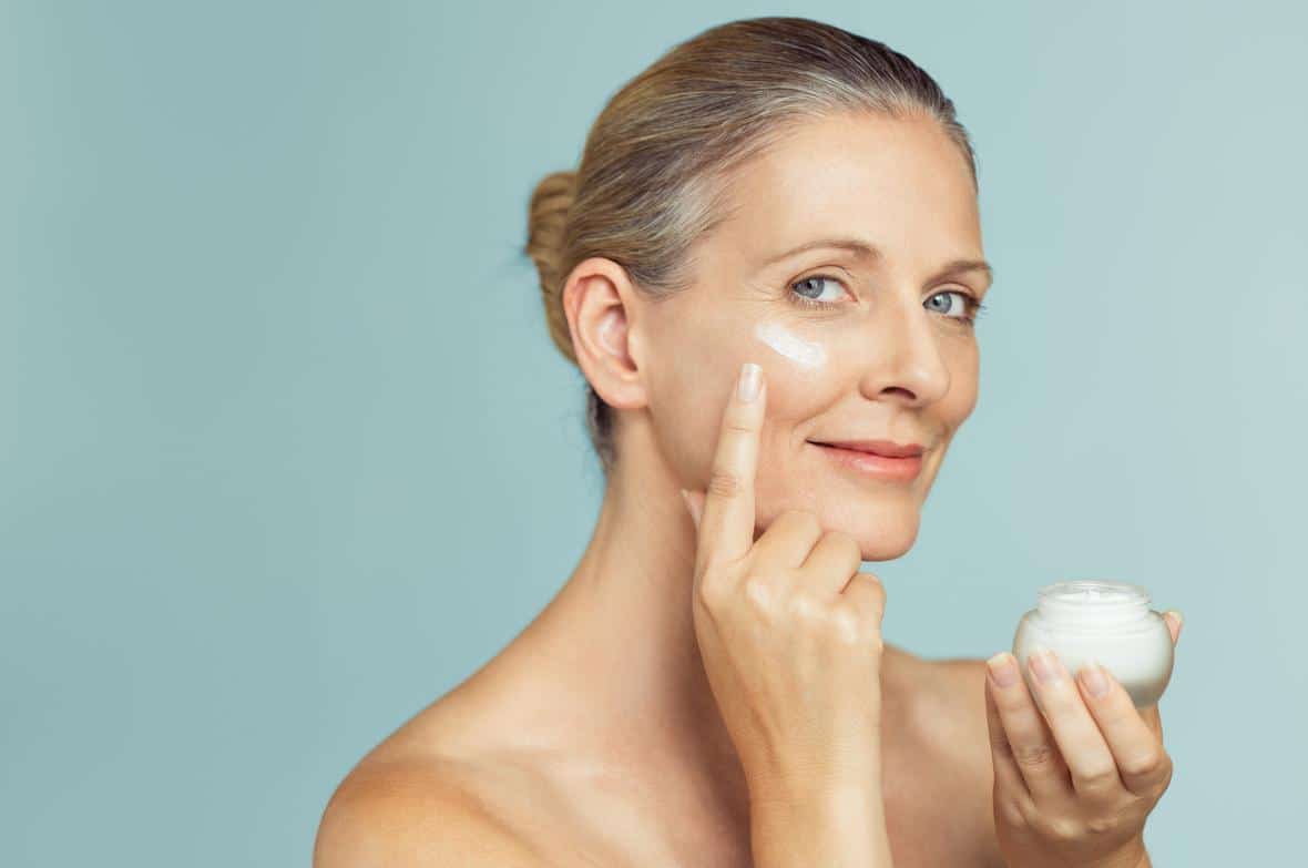 A woman applying cream to her face